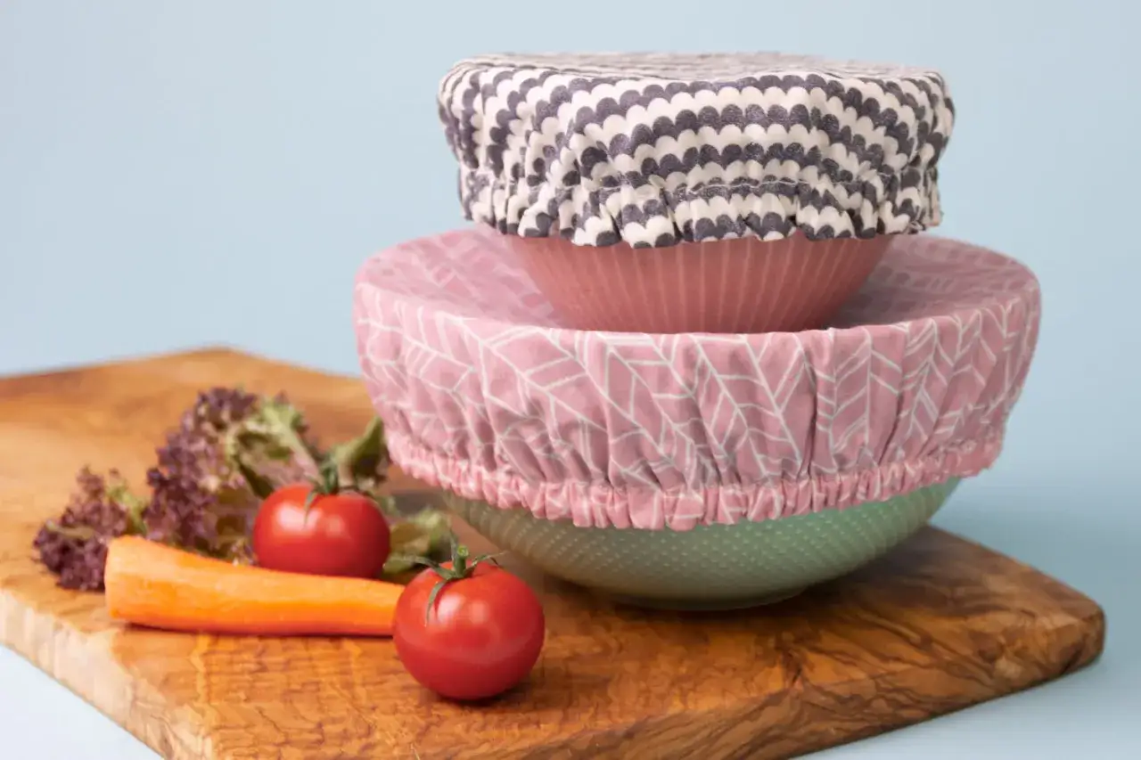Trois couvre-plats en tissu, parfaits pour un tuto DIY. Des carottes, tomates et salades sur une planche en bois.