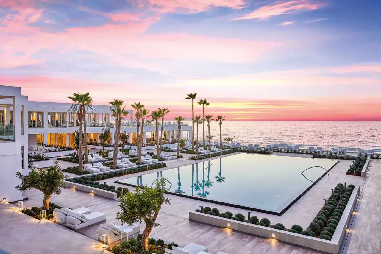 Luksusowy hotel z basenem i palmami nad morzem. Idealne miejsce na wakacje grecja all inclusive 2026.