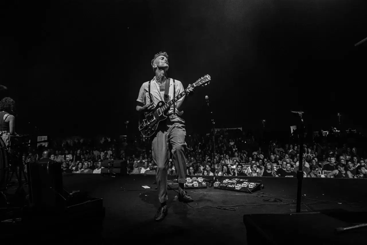 Asaf Avidan spielt in Berlin. Ein Mann mit Gitarre auf der B&uuml;hne, das Publikum im Hintergrund.