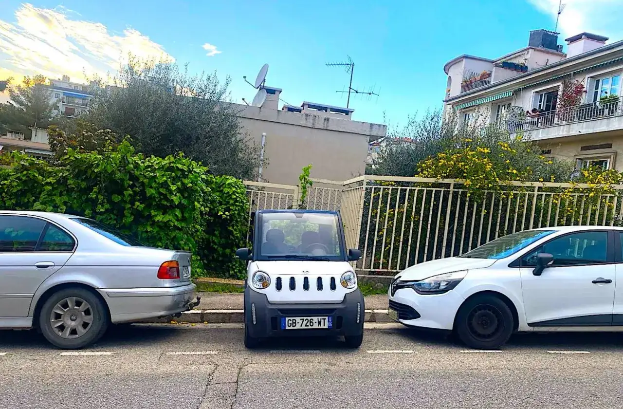 Trois voitures garées côte à côte. La petite voiture blanche au centre, avec son petit rayon de braquage, semble parfaite pour les rues étroites.