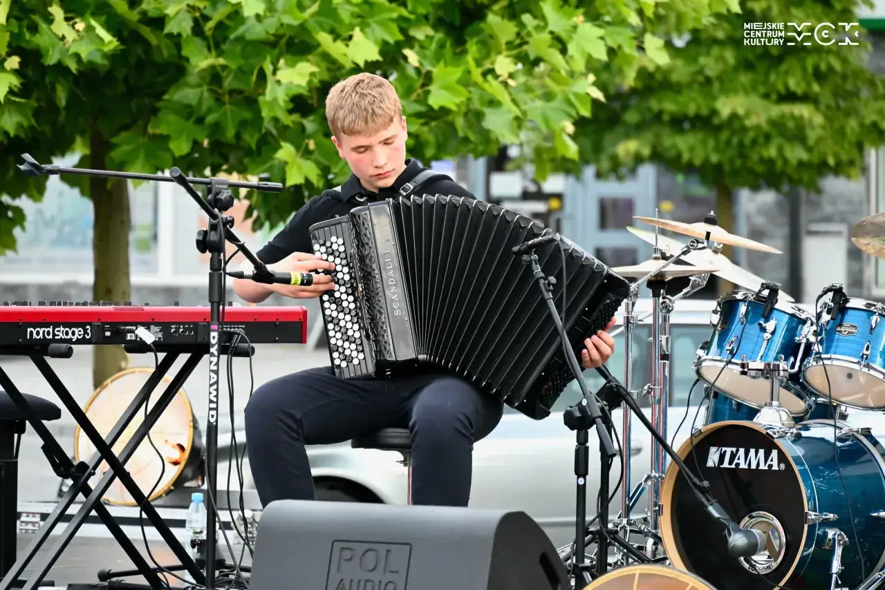 Młody akordeonista gra znane utwory na akordeon. W tle perkusja i keyboard.