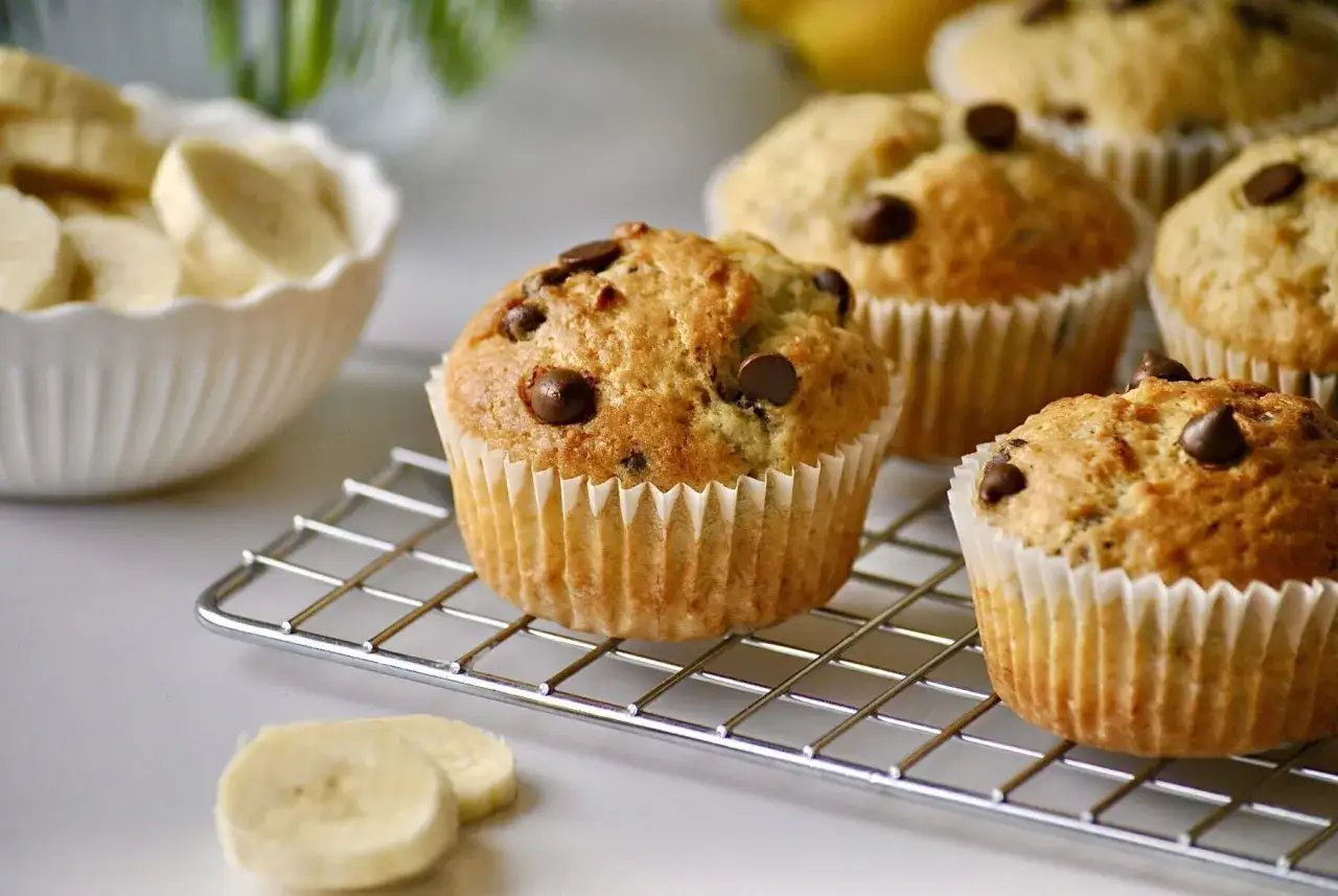 Frisch gebackene Bananen-Schoko-Muffins auf einem Gitter. Perfekt f&uuml;r die Backzeit!