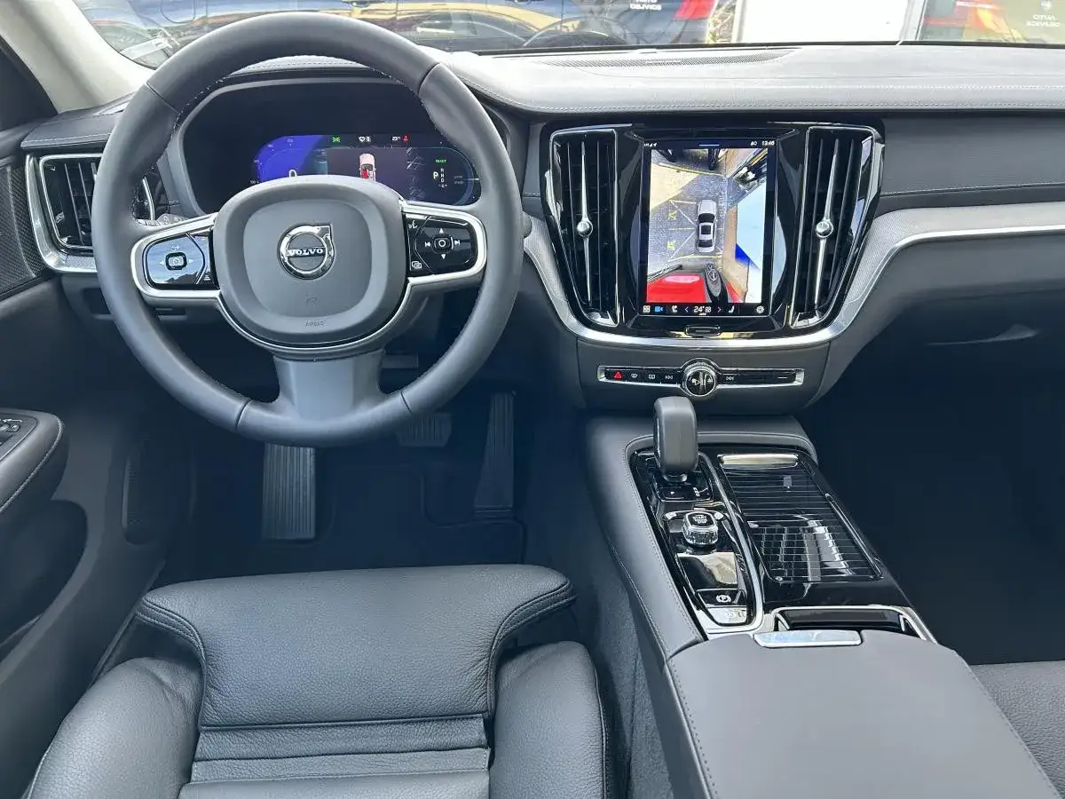 Wnętrze Volvo S60 T8: kierownica, cyfrowy kokpit i ekran multimediów z widokiem z kamery cofania.