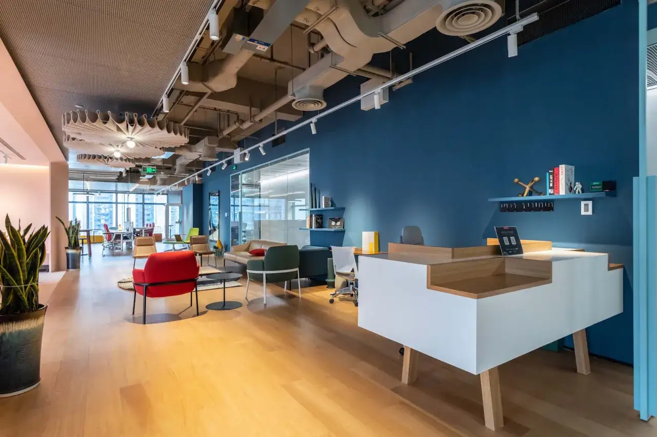 Aménagement espace accueil moderne avec mobilier design, murs bleus et parquet clair.
