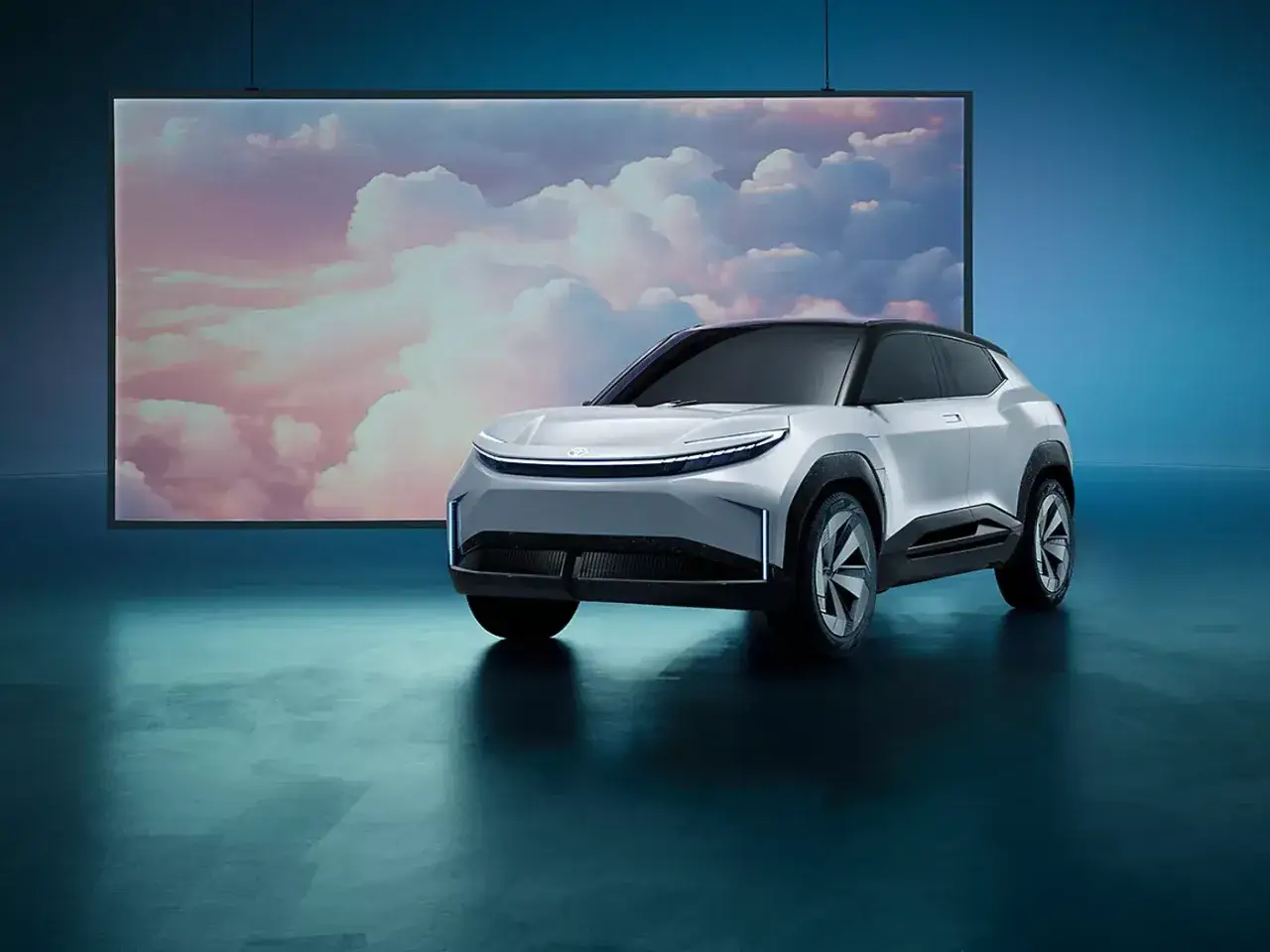 Un coche el&eacute;ctrico futurista, una de las novedades coches, se presenta ante un fondo de nubes rosadas y celestes.