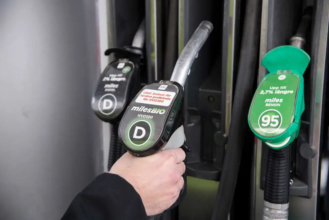 Hand håller dieselpump för personbil. En annan pump för bensin syns bredvid.