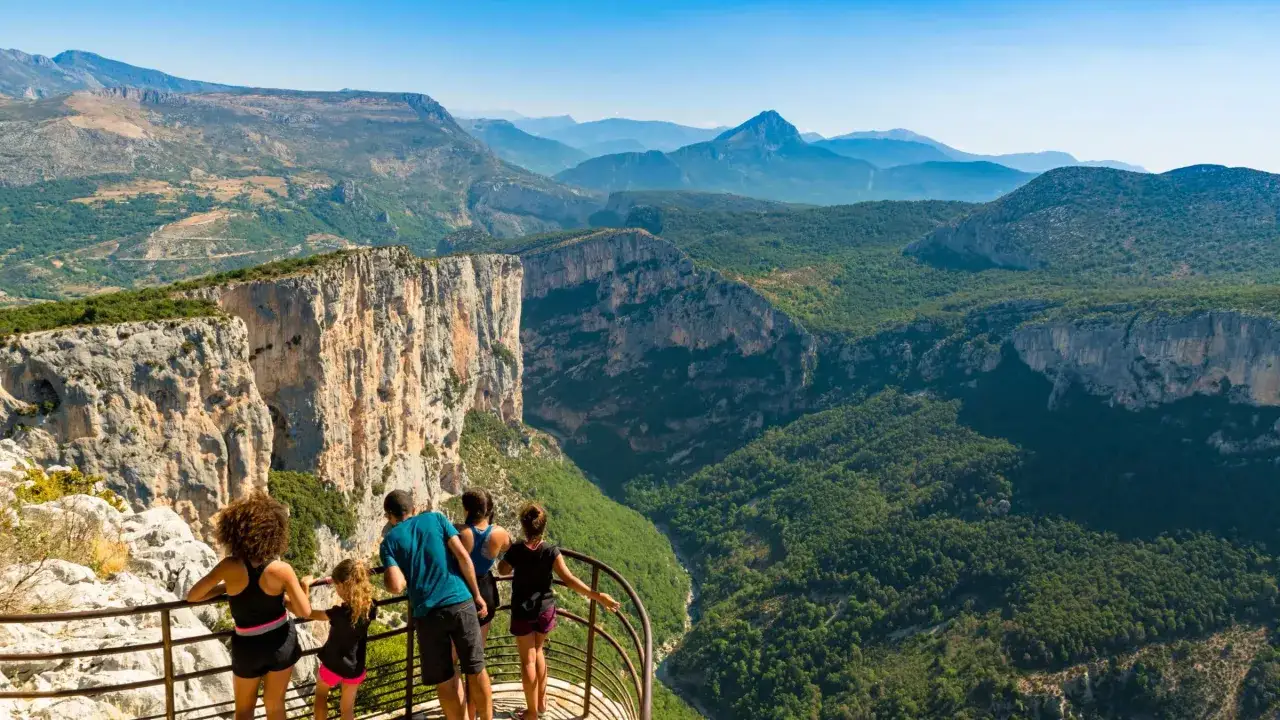 Famille admirant le panorama spectaculaire des Gorges du Verdon lors d'une randonn&eacute;e. Le soleil brille sur les falaises et la v&eacute;g&eacute;tation luxuriante.