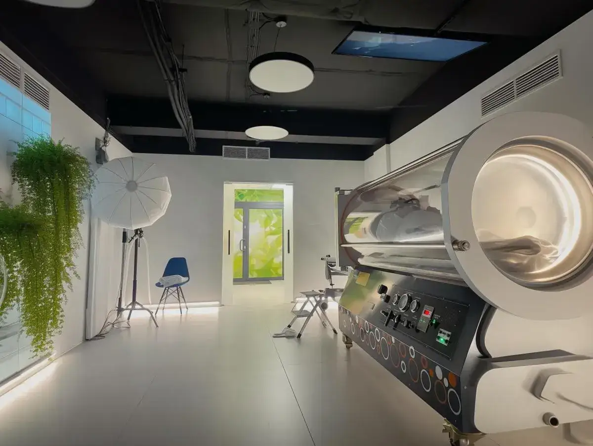 Komora hiperbaryczna na co pomaga? Wnętrze kliniki z nowoczesną komorą tlenową, gdzie pacjent leży w środku, przygotowany do terapii.