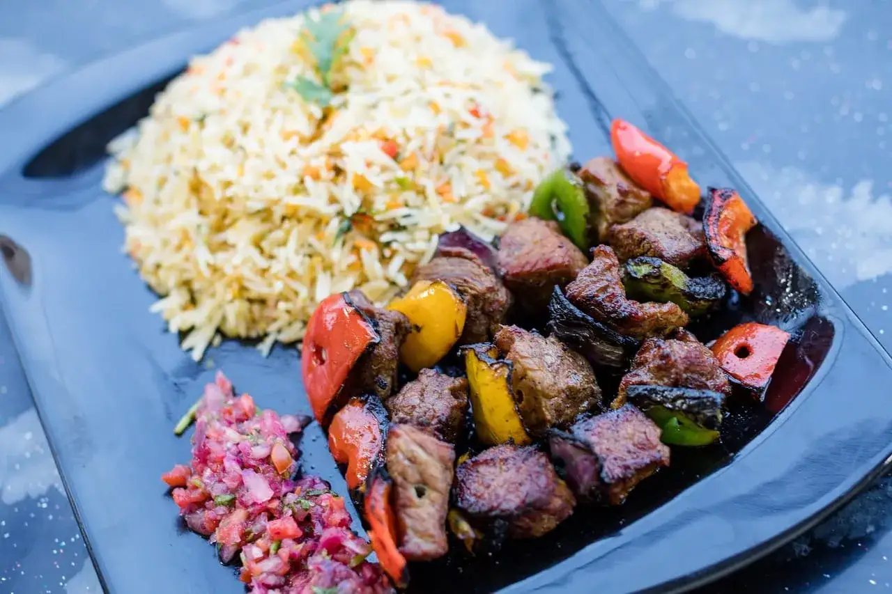 Szukasz odpowiedzi na pytanie: kuchnia fusion co to? Oto danie z grillowanymi szaszłykami z wołowiny i warzyw, podane z ryżem i salsą.