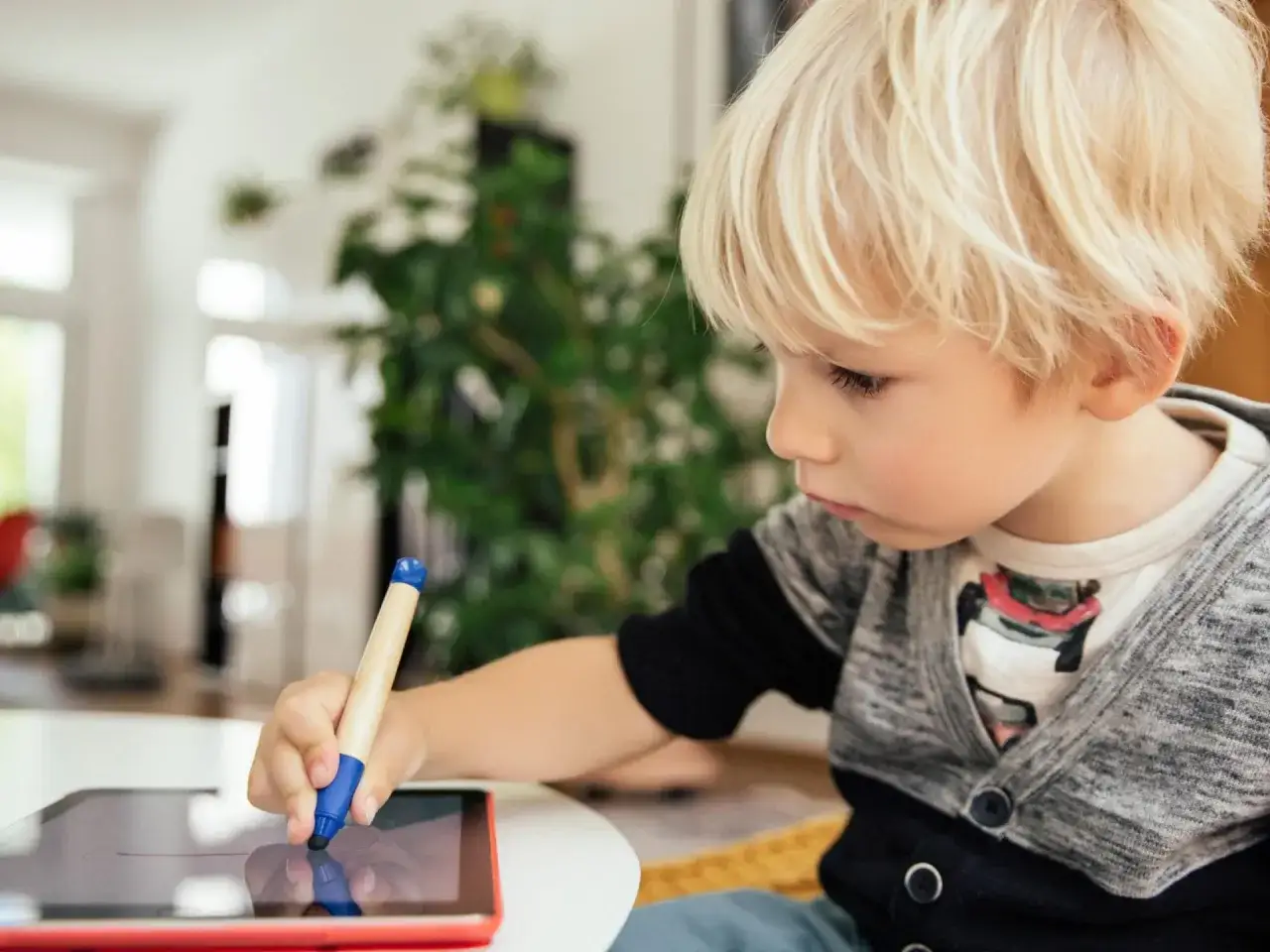 Ein Junge &uuml;bt mit einem Stift auf einem Tablet, vielleicht f&uuml;r online diktate.