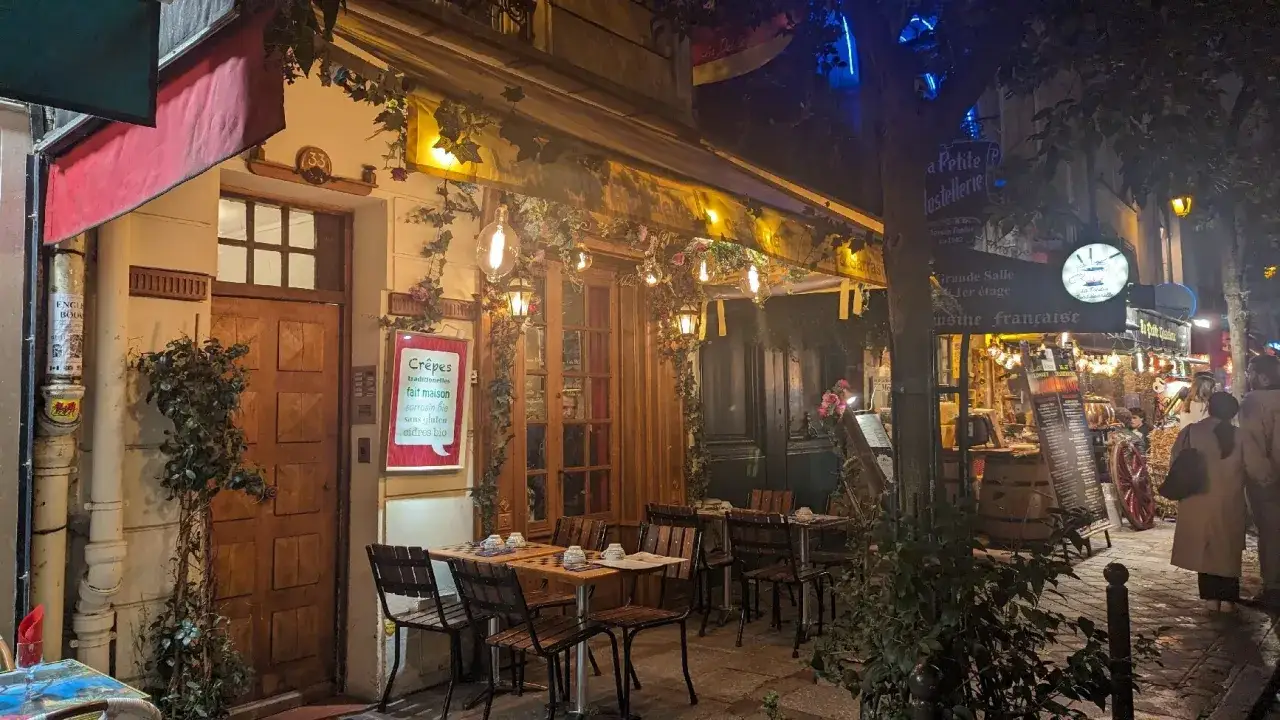 Charmante crêperie illuminée la nuit, parfaite pour savoir **ou manger après minuit**. Tables dressées, lierre et guirlandes lumineuses créent une ambiance féerique.