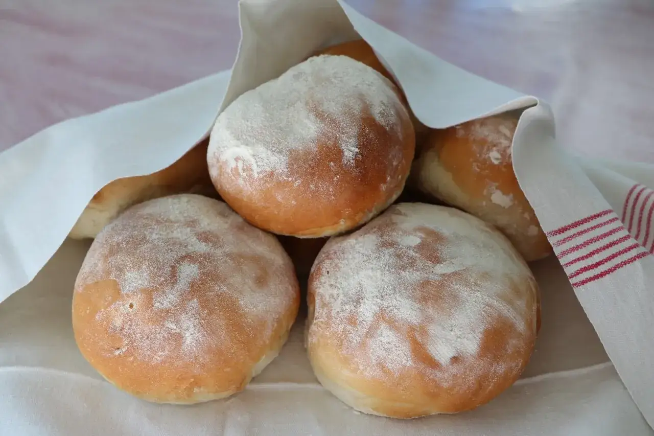 Nybakade frallor, pudrade med mjöl, redo att avnjutas. Ett enkelt frallor recept för hemmabruk.