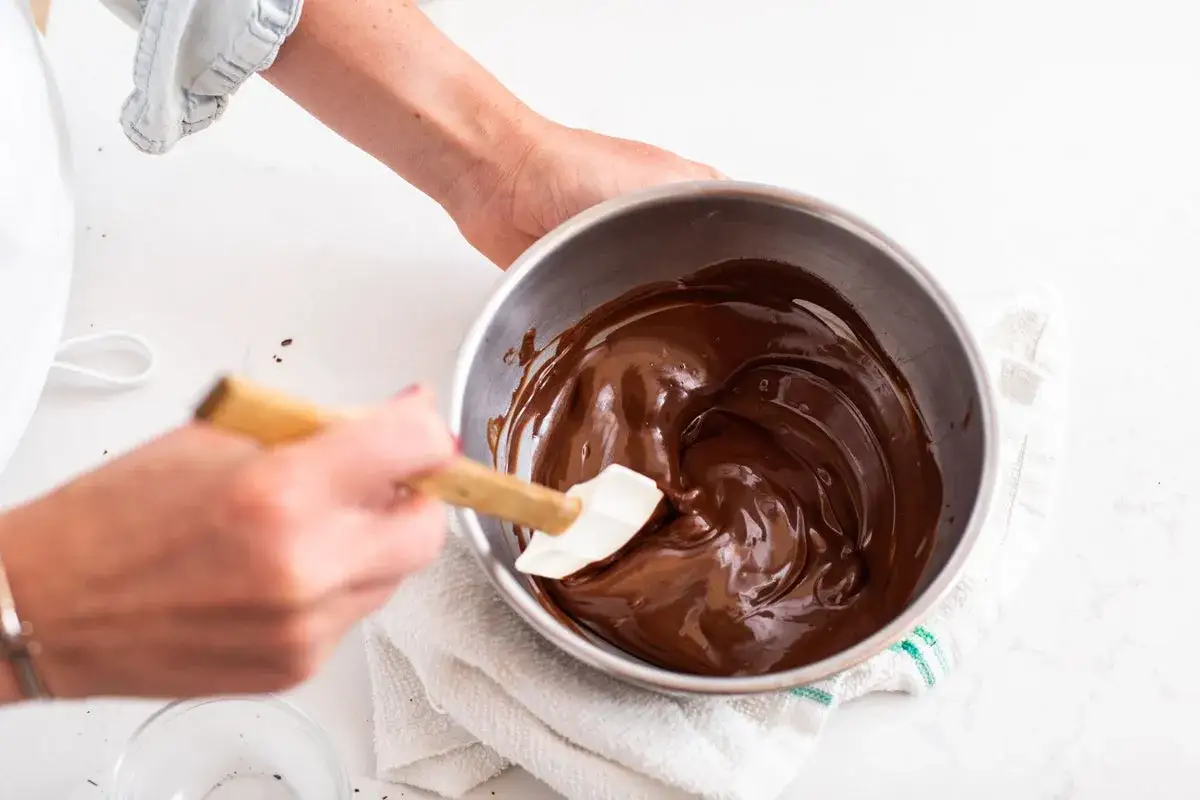 Mains douces pour faire chocolat fondu, m&eacute;langeant la texture soyeuse dans un bol en m&eacute;tal.