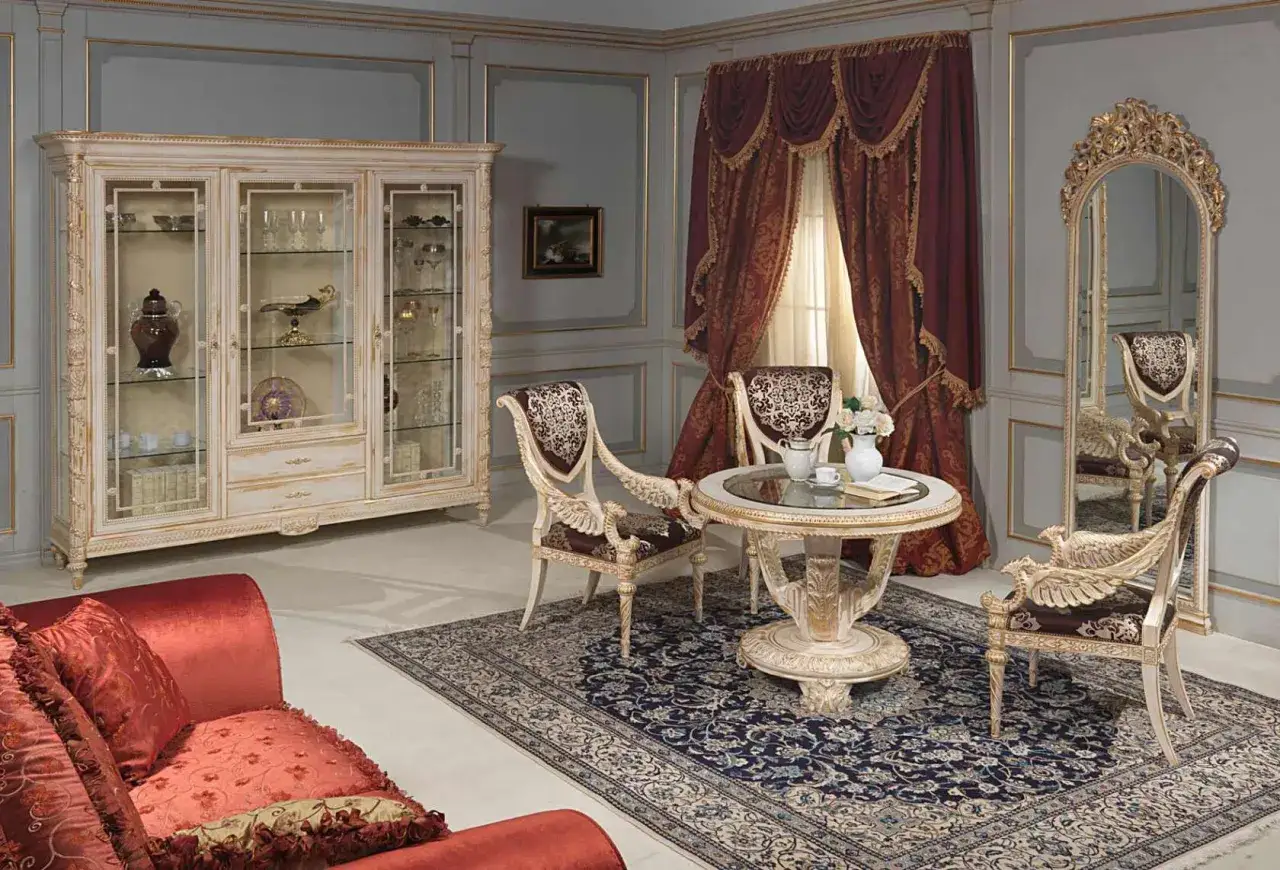 Salon de style Louis XVI avec vitrine, table ronde, chaises sculpt&eacute;es, tapis persan et rideaux de velours.