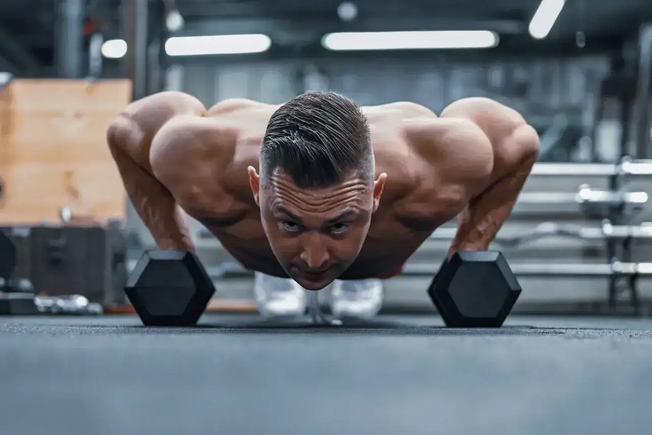 Mężczyzna wykonuje pompki na biceps z hantlami. Intensywny trening mięśni ramion.