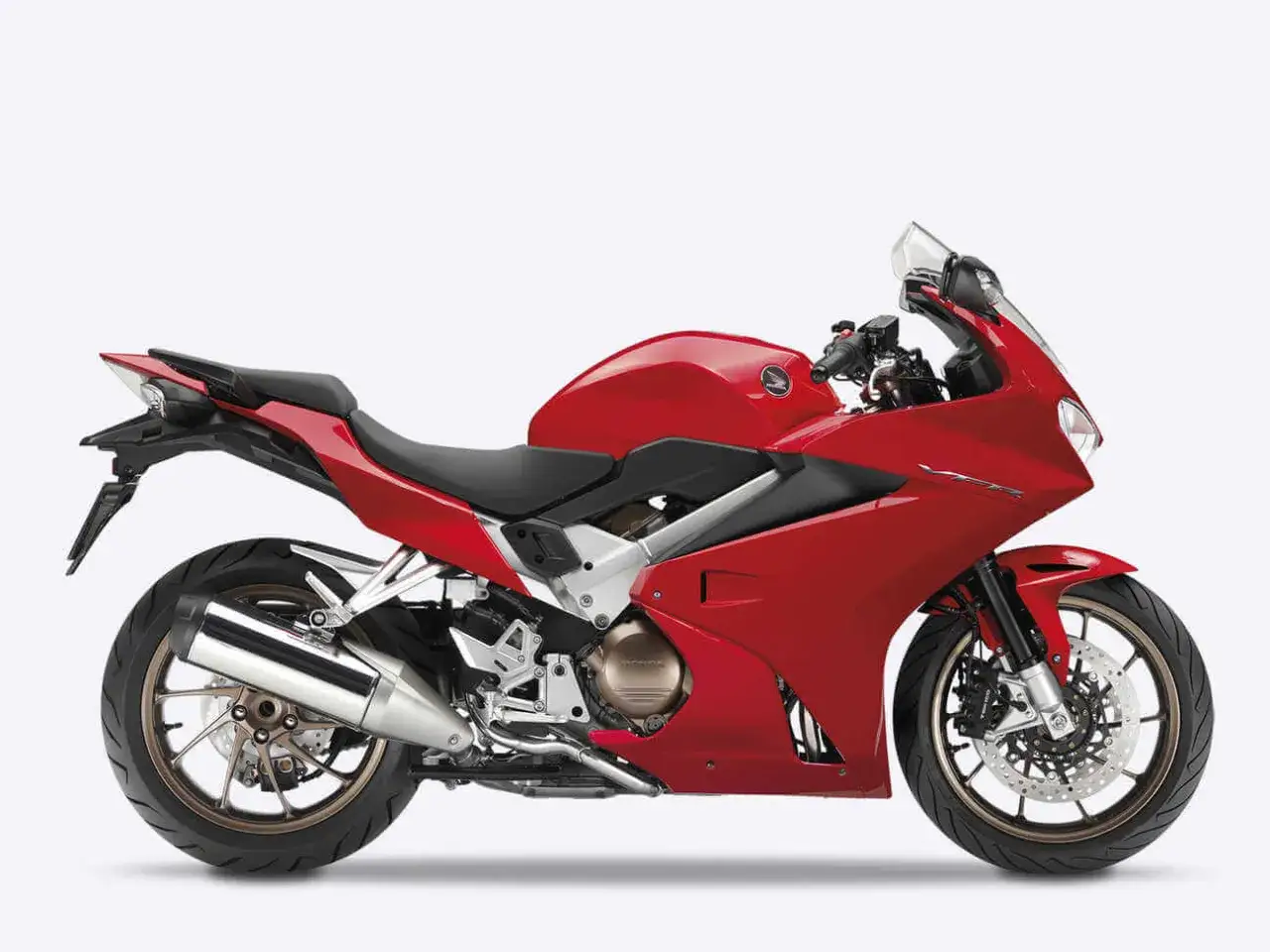 Czerwony motocykl sportowy Honda VFR 800 z błyszczącym wydechem i brązowymi felgami, gotowy do jazdy.