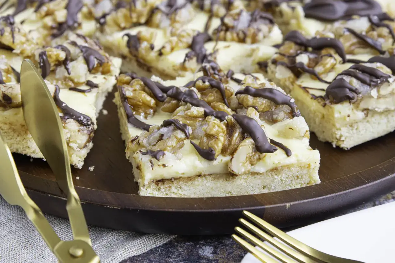 Saftiger Friss dich dumm Kuchen vom Blech mit N&uuml;ssen und Schokoglasur auf einem Holzteller.