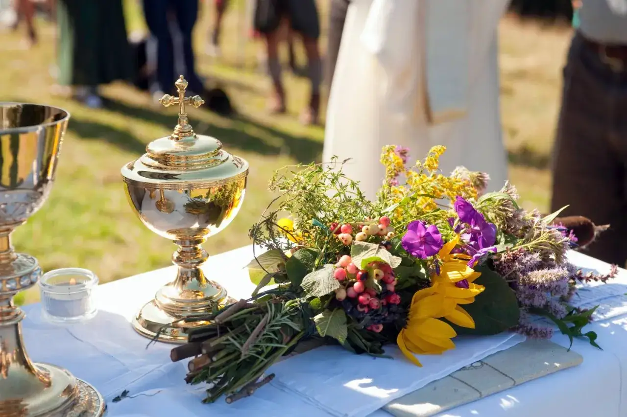 Goldener Kelch und Blumenstrauß auf weißem Tuch. Eine feierliche Atmosphäre am 15. August.