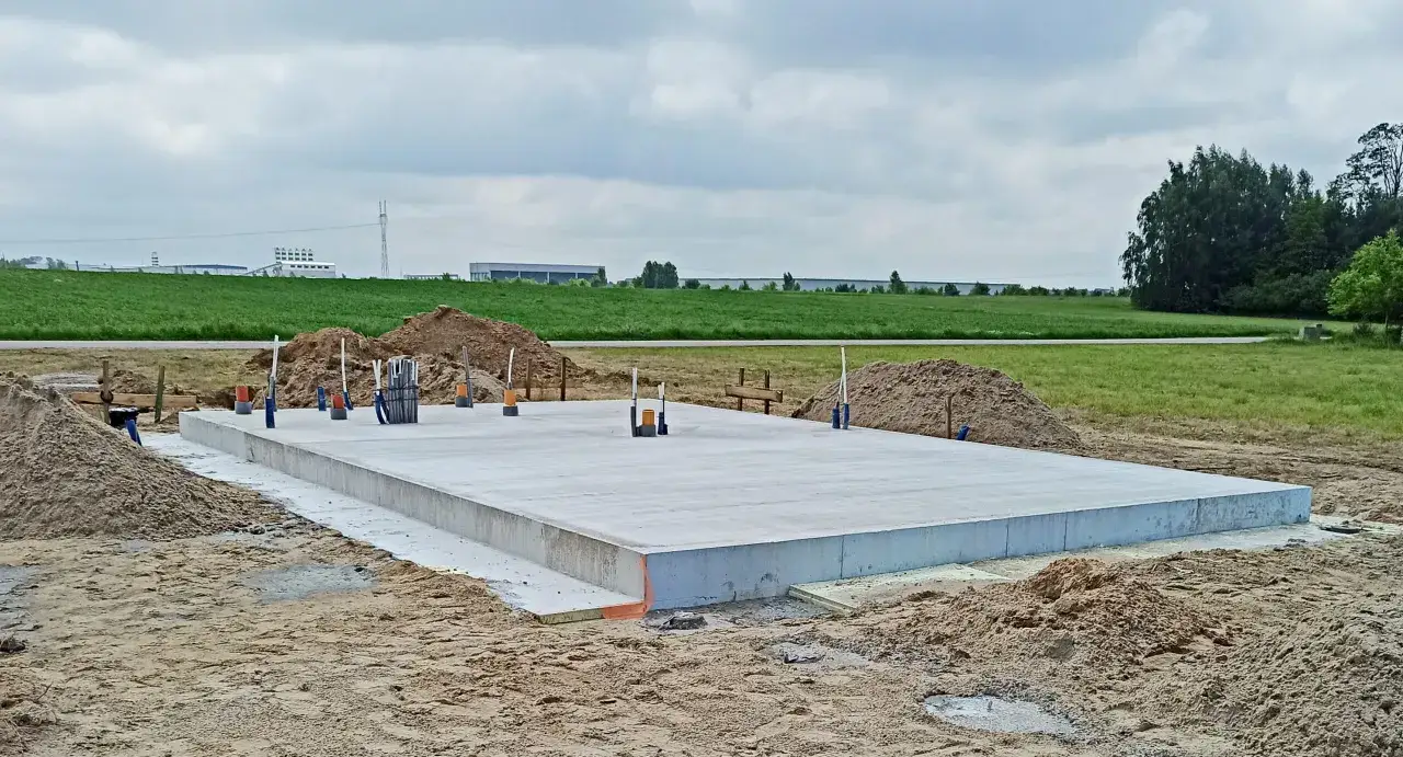 Gotowy fundament pod budowę domu. Widać zbrojenie i przygotowanie do dalszych prac. To pierwszy krok, jak wykonać fundament.