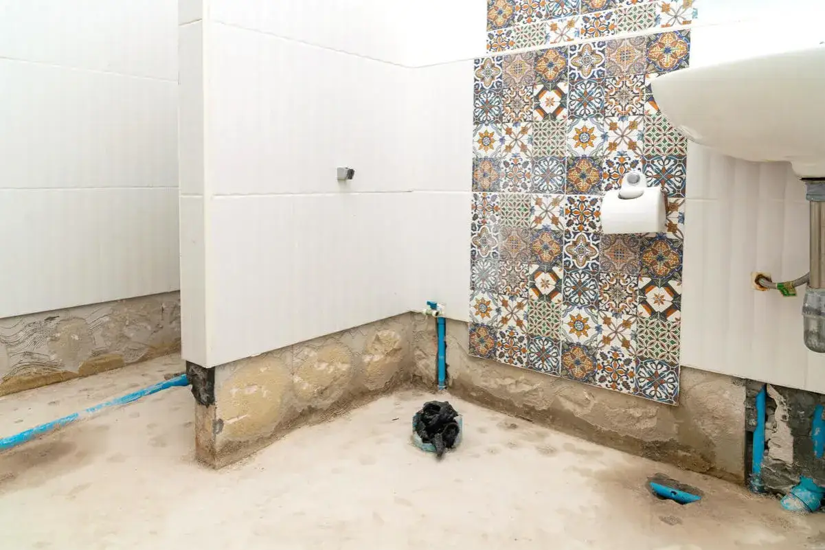 Renovering av badrum. V&auml;ggarna &auml;r kaklade, men golvet och nedre delen av v&auml;ggarna &auml;r oklara. En toalettrulle h&auml;nger p&aring; en v&auml;gg med m&ouml;nstrat kakel. Kanske dags att m&aring;la v&aring;trumsmatta?