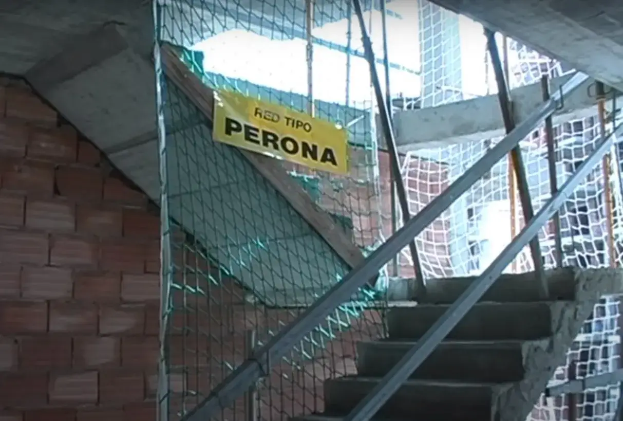 Escalera en construcción con red de seguridad tipo Perona y ladrillos a la vista.