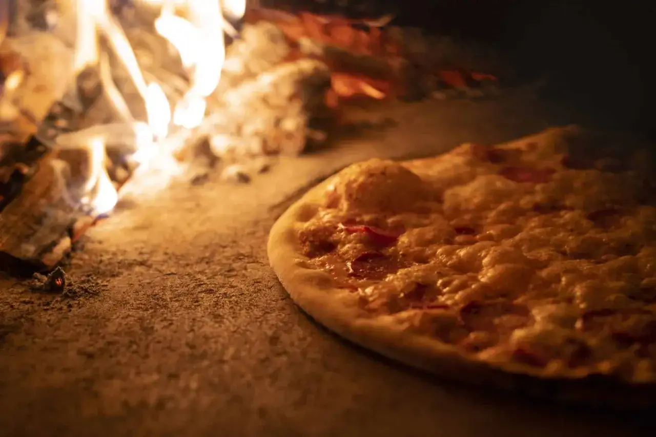 Flammekueche dorée et croustillante cuisant dans un four à bois, la vraie recette pour un goût authentique.