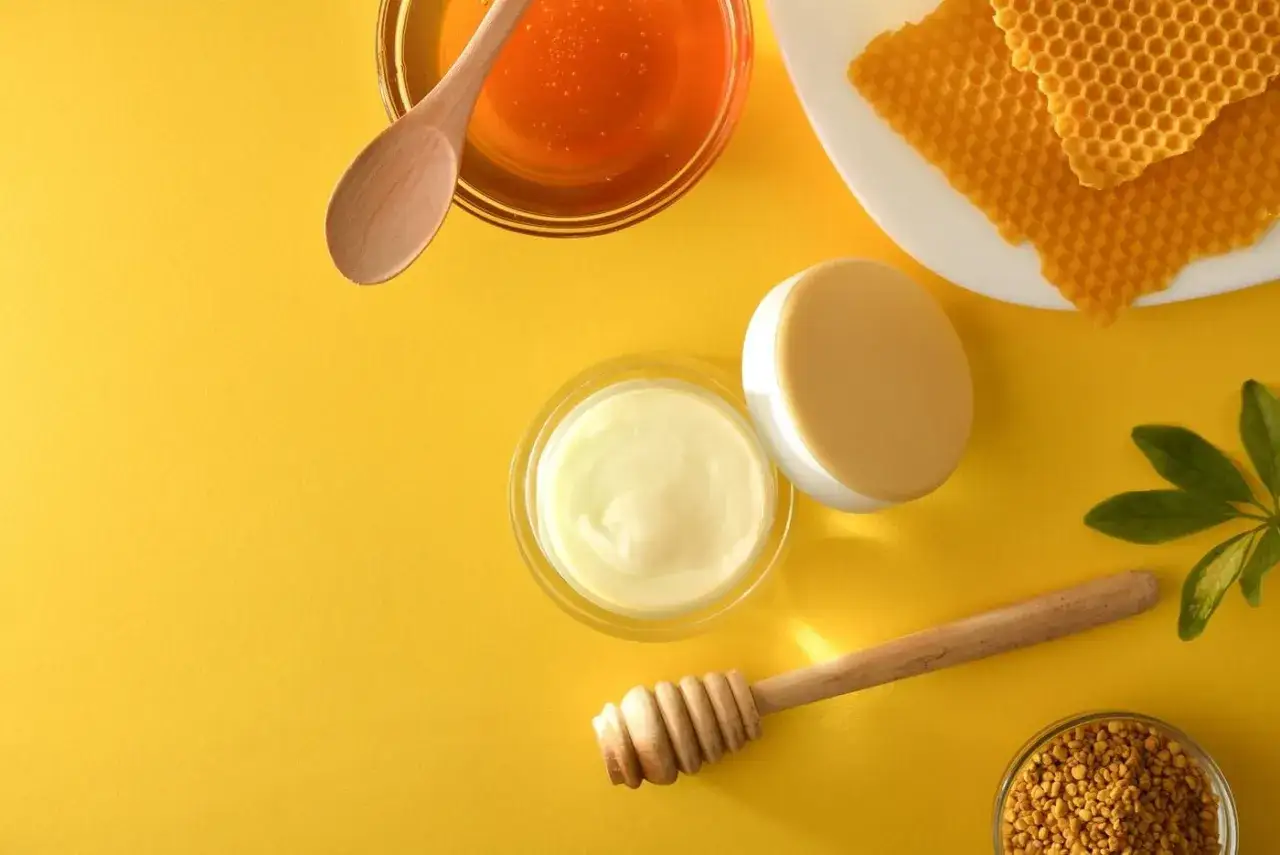 Słoik z kremem, miód, plastry pszczele i pyłek – naturalne składniki podkreślające propolis właściwości.
