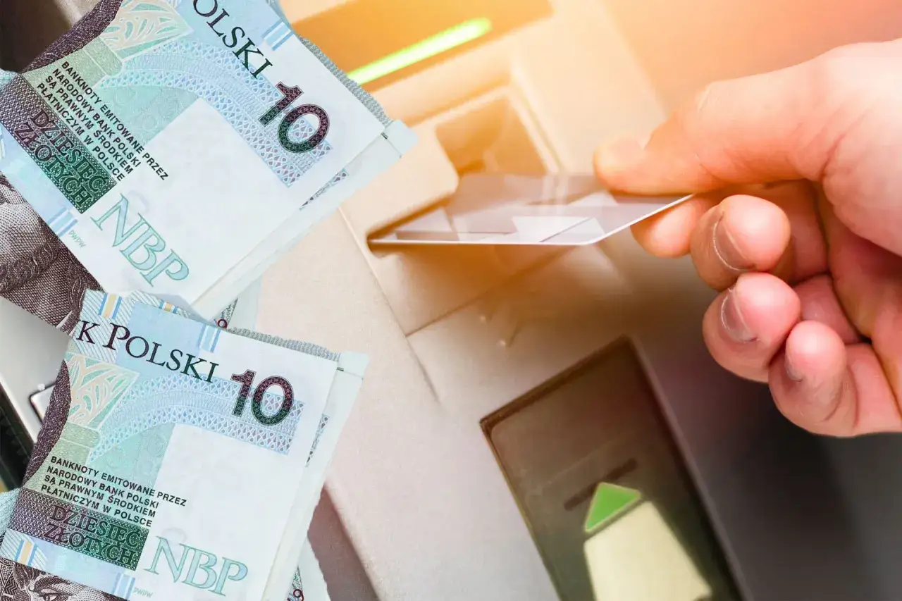 Ręka wsuwa kartę do bankomatu, obok leżą banknoty 10 zł. To jak zawiadomienie o uchyleniu zajęcia, pieniądze wracają do obiegu.