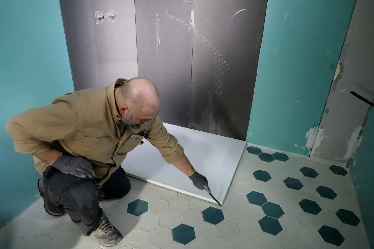 Un homme installe un receveur douche r&eacute;sine, peut-&ecirc;tre pour &eacute;viter un inconv&eacute;nient de pose.
