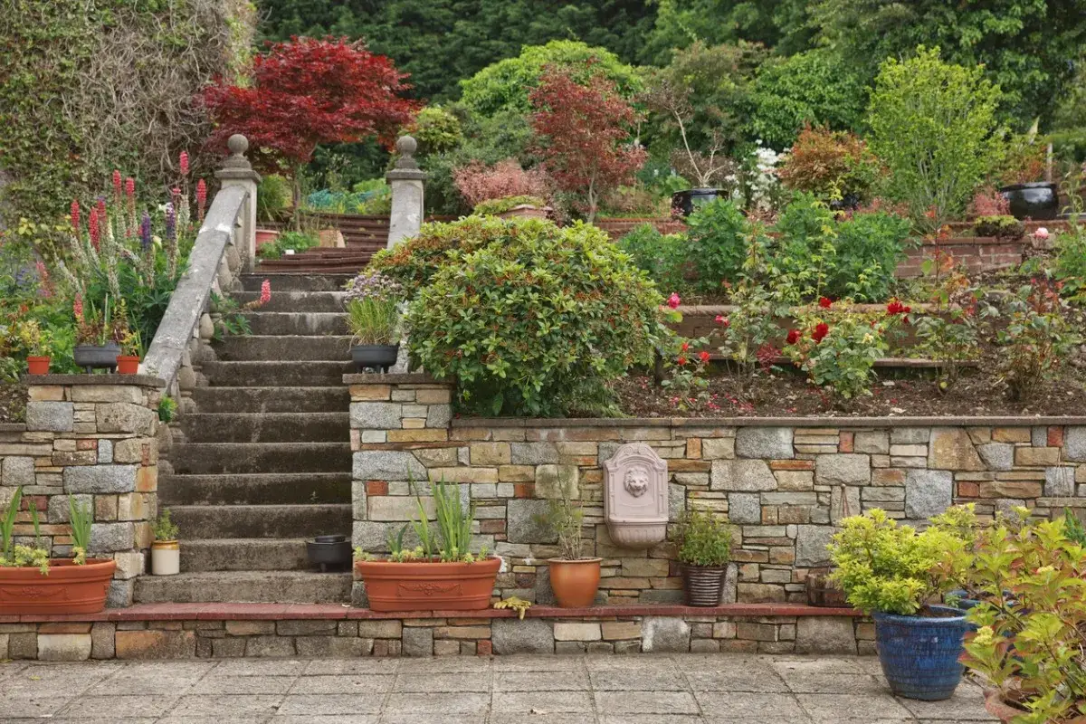 Steinmauer im Garten mit Treppen und &uuml;ppiger Bepflanzung. Tolle Steinmauer Garten Ideen f&uuml;r ein nat&uuml;rliches Ambiente.