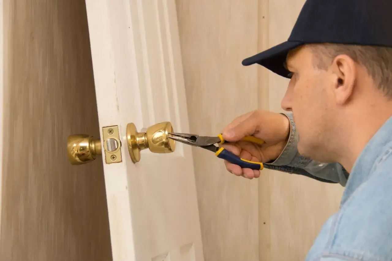 Un homme utilise une pince pour tenter de comment enlever de la colle dans une serrure de porte.
