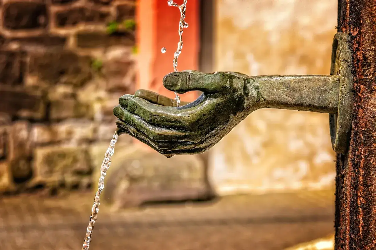 Kamienna dłoń, z której cieknie woda, symbolizuje bezradność wobec upływu czasu i przemijania.