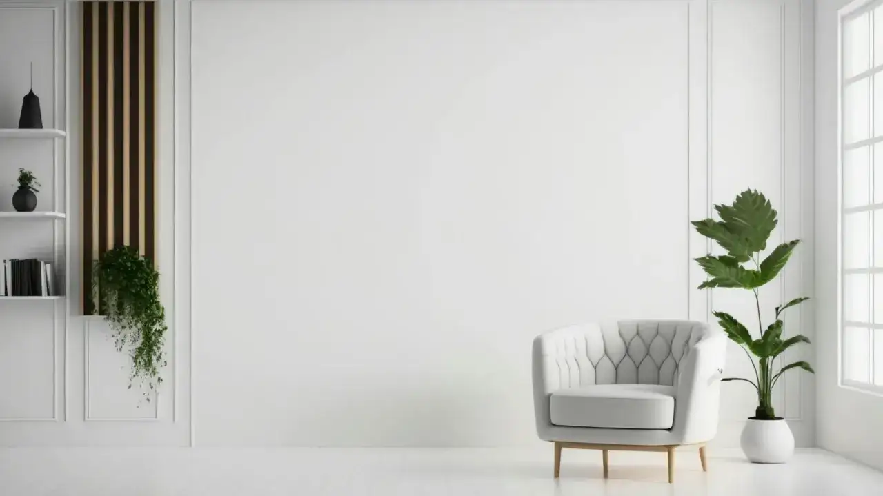 Minimalistyczny salon z białymi ścianami, na kt&oacute;rych widać subtelne zdobienia. W rogu stoi wygodny fotel, a obok niego duża roślina. Na p&oacute;łkach widać książki i dekoracje. Całość sprawia wrażenie czystości i spokoju, jakby ściany pokrywała wysokiej jako...