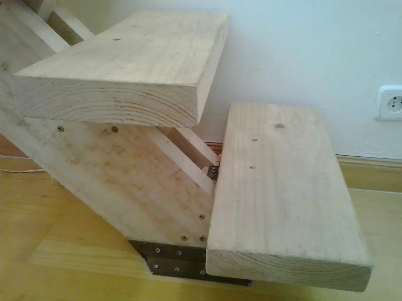 Detalle de una escalera de madera en construcci&oacute;n, con pelda&ntilde;os de pino y soportes met&aacute;licos.