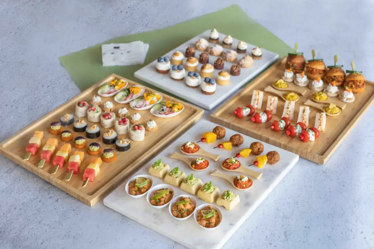 Plateaux variés de bouchées, dont des brochettes de fruits, des mini-rouleaux, des verrines végétariennes et des mini-burgers.