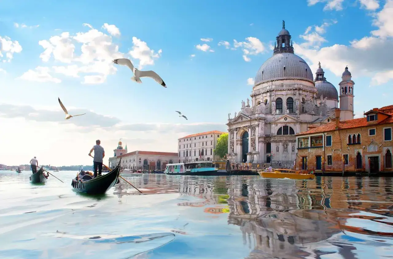 Gondole scivolano sull'acqua a Venezia, con gabbiani in volo e la Basilica di Santa Maria della Salute sullo sfondo, un'opera d'arte che ricorda un museo d'arte contemporanea a Venezia.