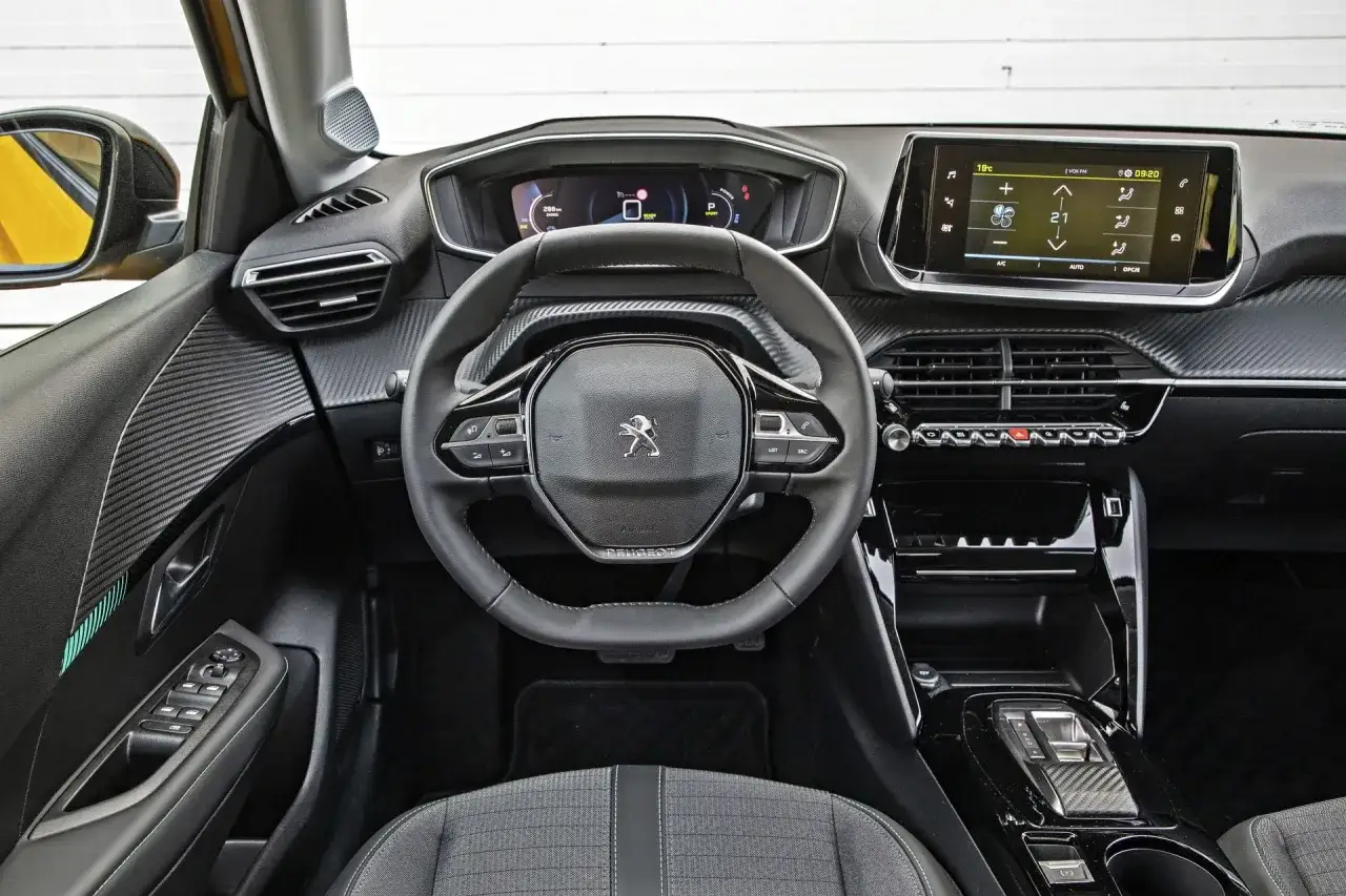 Wnętrze Peugeot e-208 z cyfrowym kokpitem, ekranem dotykowym i sportową kierownicą.