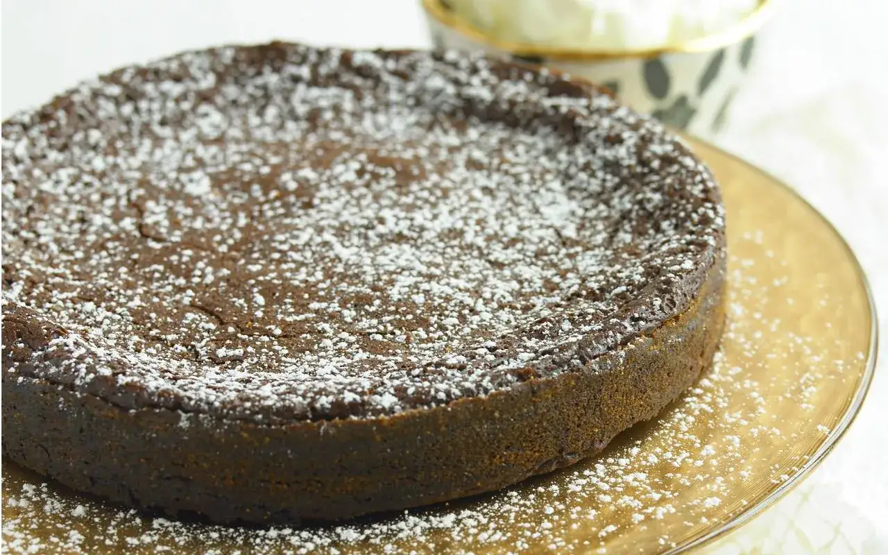 En m&ouml;rk chokladkaka, pudrad med florsocker, ligger p&aring; ett guldf&auml;rgat fat. Den ser ut som en perfekt lava cake.