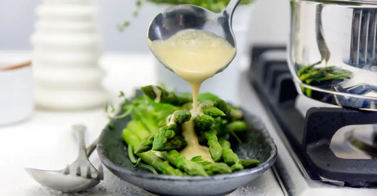 Sparris serveras med en kr&auml;mig beurre blanc-s&aring;s som h&auml;lls &ouml;ver fr&aring;n en slev.