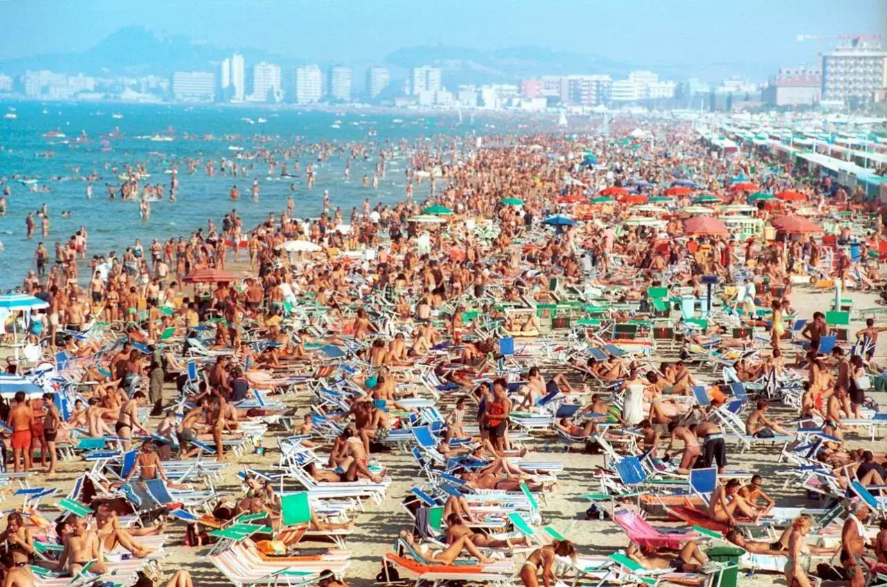Folla immensa sulla spiaggia per il **Ferragosto in Riviera Romagnola**. Ombrelloni, lettini e bagnanti in un mare di gente.