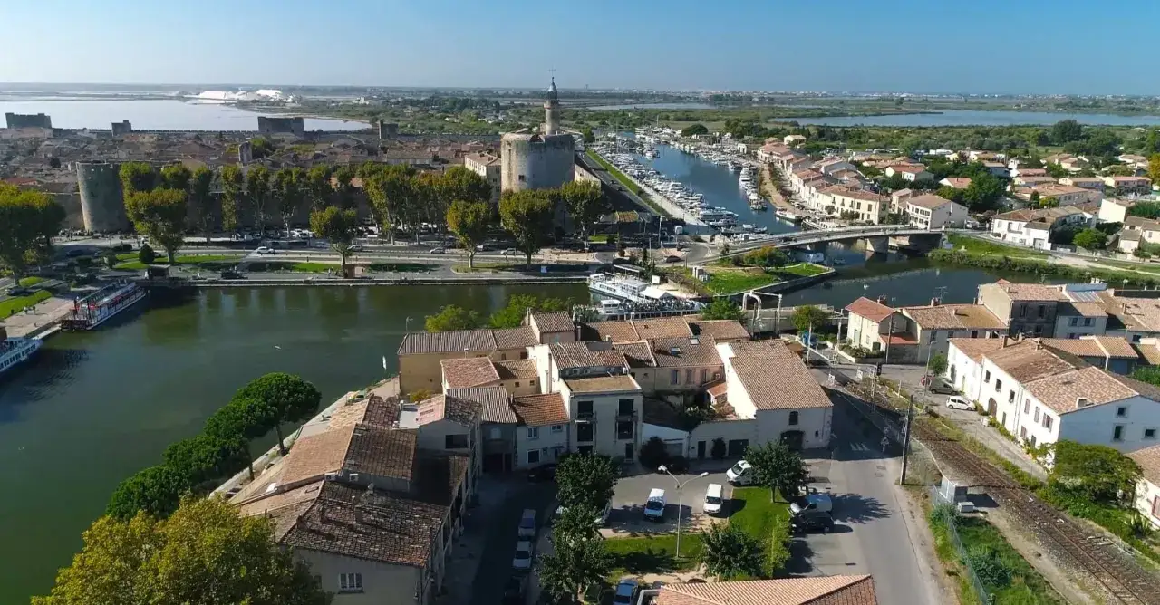 Vue aérienne d'une ville avec un port de plaisance, des remparts et un canal. Une belle **location avec promesse de vente** idéale pour les amoureux de la mer et de l'histoire.