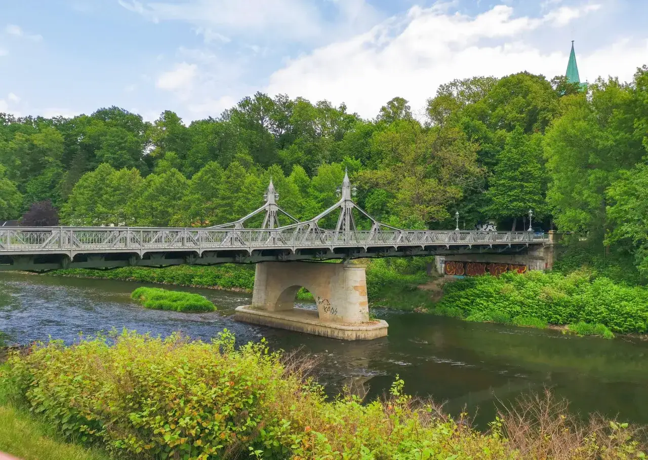 Eine historische Br&uuml;cke &uuml;berspannt einen Fluss, umgeben von &uuml;ppigem Gr&uuml;n. Ein echter **Geheimtipp Zwickau** f&uuml;r Naturliebhaber.