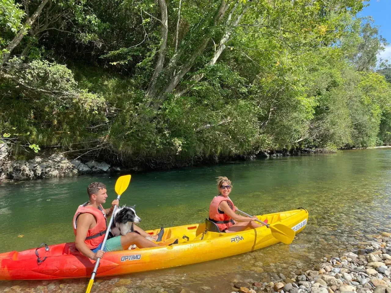 Disfrutando de un paseo en kayak por un r&iacute;o en Cantabria con ni&ntilde;os y un perro.