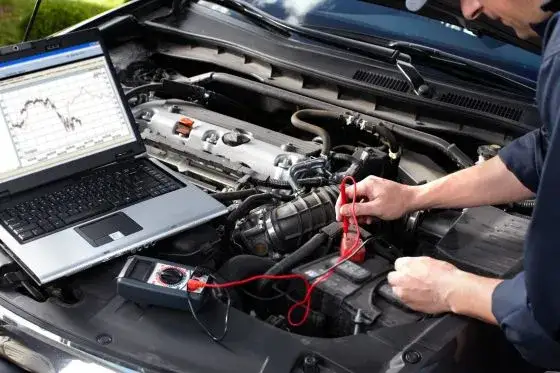 Mechanik podłączający komputer diagnostyczny do samochodu