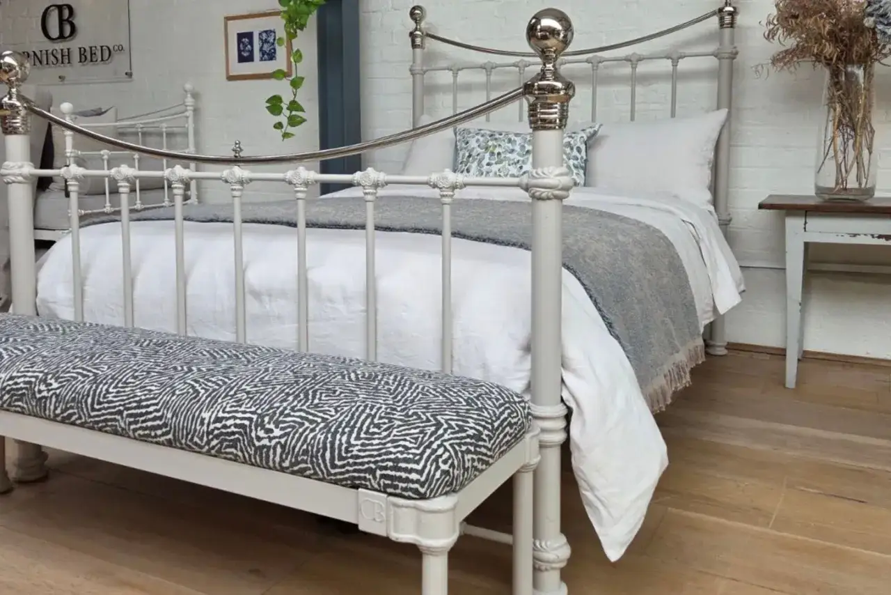 A bench with a striking black and white patterned cushion sits at the foot of a king bed. This bench is a perfect size for a king bed, adding style and function.