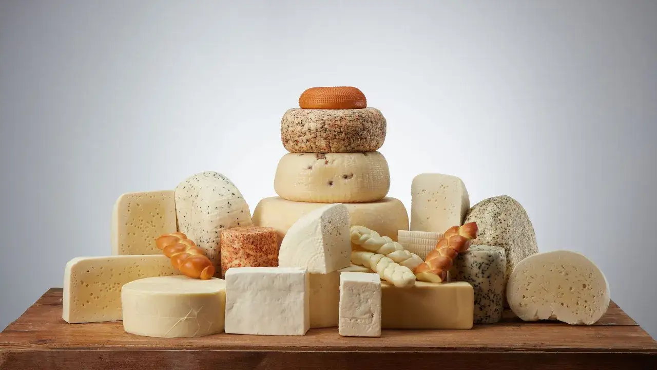 Varietà di formaggi, tra cui formaggio senza lattosio, disposti su un tavolo di legno.