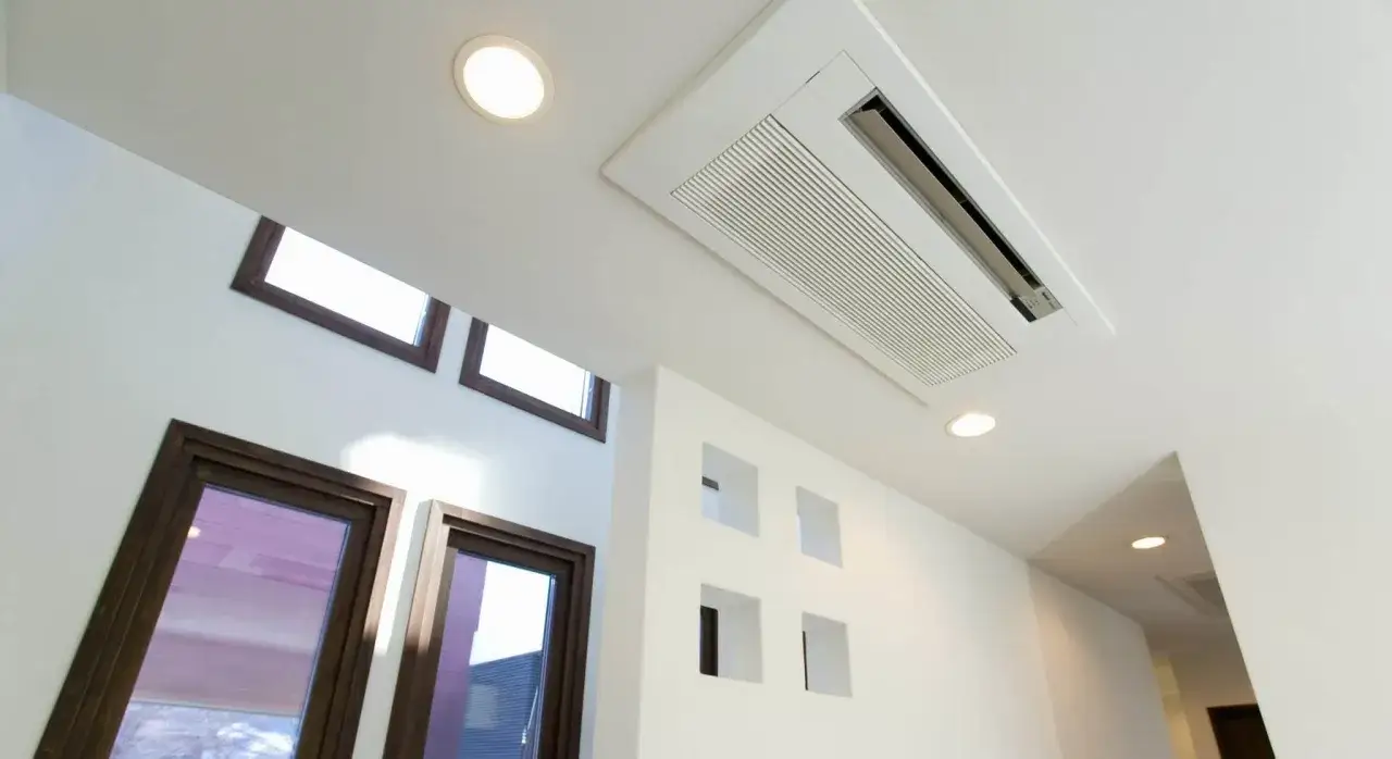 Un système de clim gainable plafond discret assure le confort dans cette pièce moderne avec ses grandes fenêtres et ses niches murales.