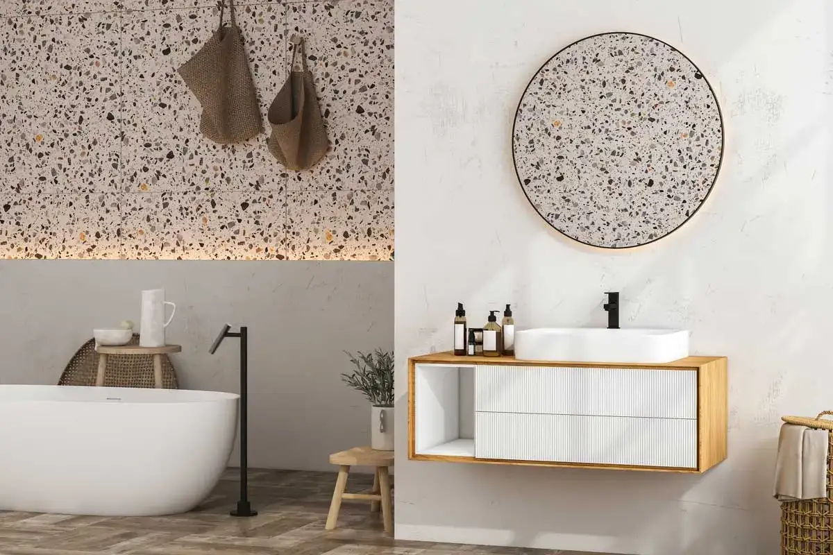 Élégante salle de bain terrazzo avec baignoire îlot, vasque moderne et miroir rond.