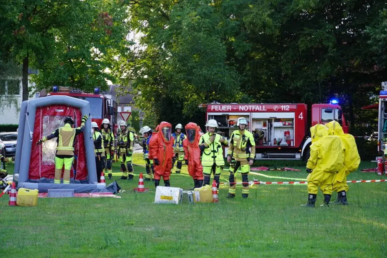 Feuerwehr-Veranstaltungen: Einsatzkr&auml;fte in Schutzanz&uuml;gen &uuml;ben den Umgang mit Dekontaminationsduschen und L&ouml;schfahrzeugen.