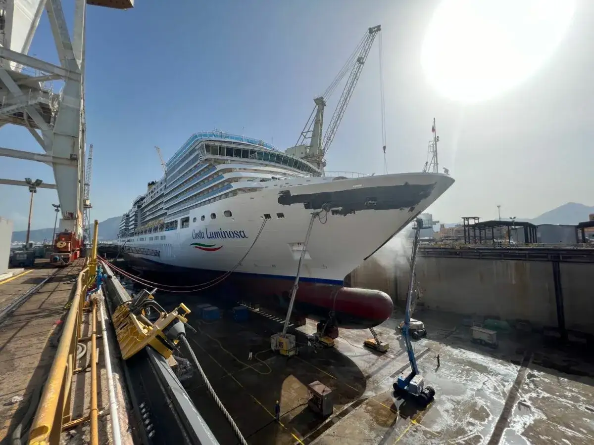 La nave da crociera Costa Luminosa in bacino di carenaggio, pronta per la manutenzione. La costa luminosa del sole illumina il cantiere navale.